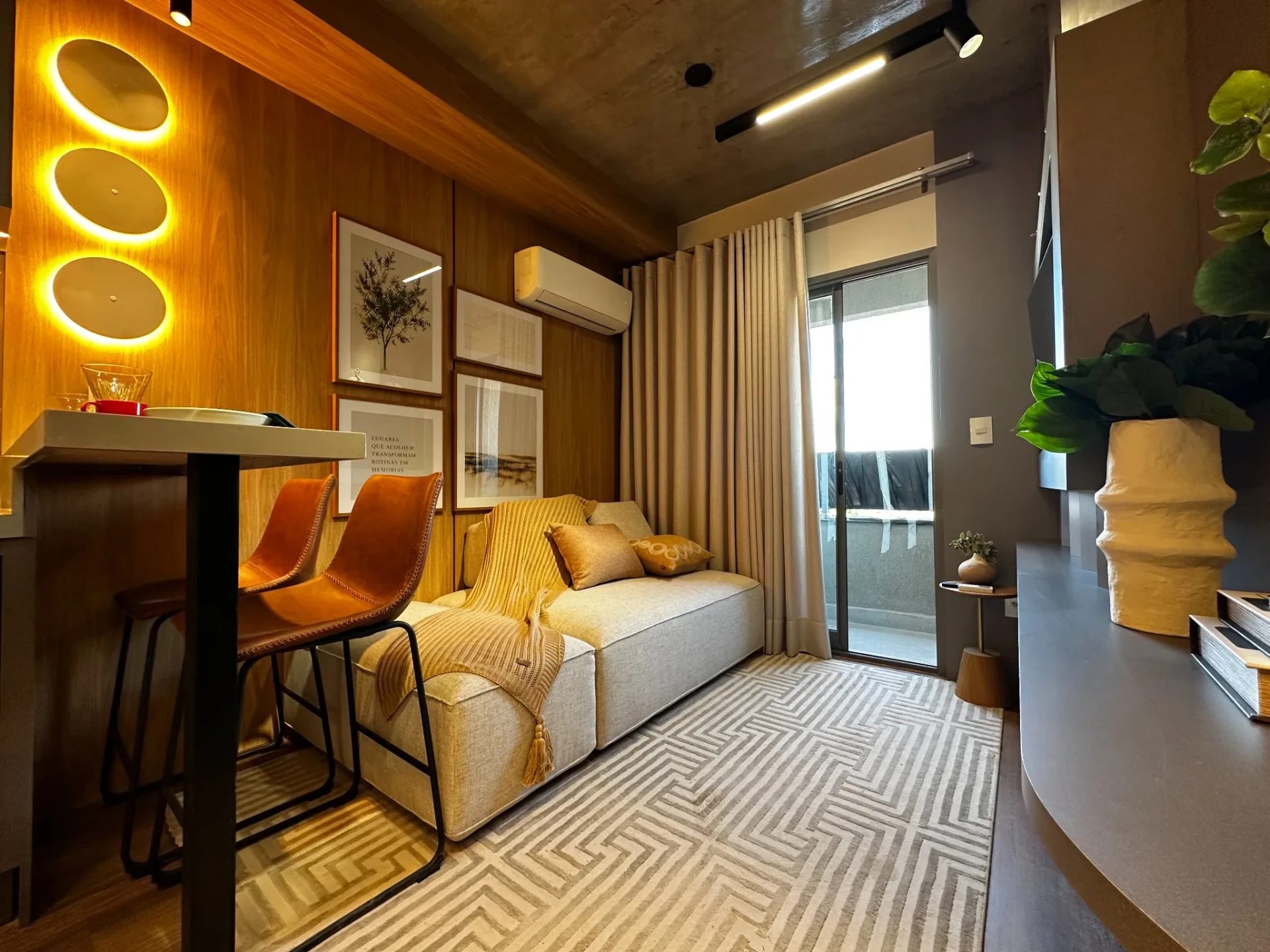 Estar do studio decorado com sofá, bancada e acesso à varanda