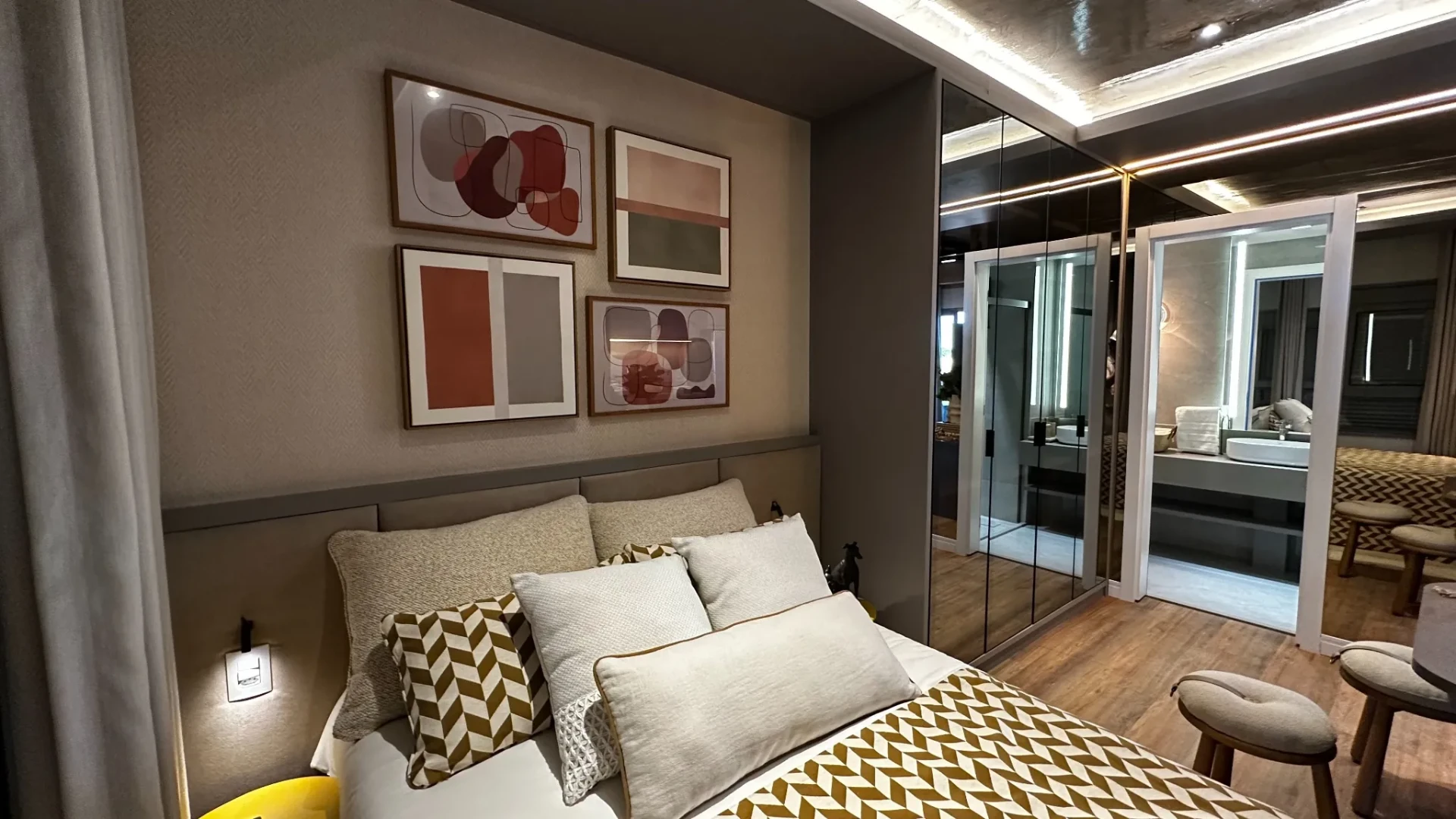 Dormitório do studio decorado com cama, quadros e armário espelhado